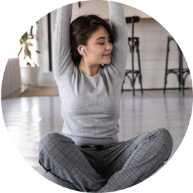 Woman sitting on the floor, stretching her arms over her head with earplugs in her ears
